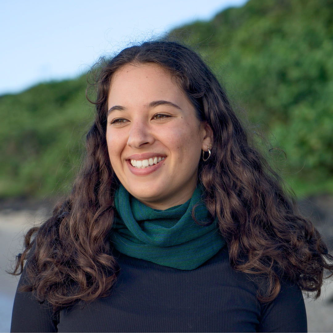 Woman with wavy hair wearing a green scarf against a natural background