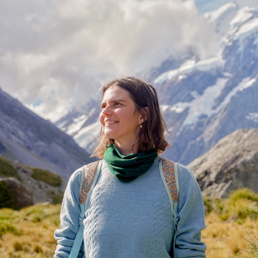 Woman standing in a mountainous landscape with snow-capped peaks.
